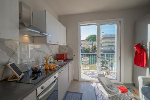una cucina con armadi bianchi e una grande finestra di Babyaccommodation Family Green a Pietra Ligure
