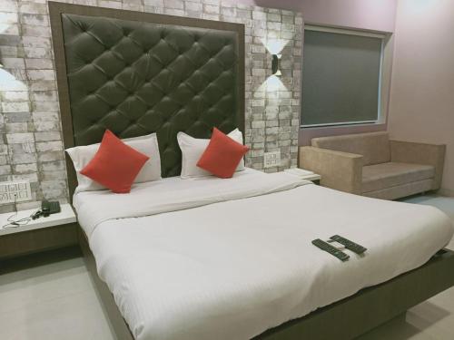 um quarto com uma cama grande e almofadas vermelhas em HOTEL AIRPORT INN ONE em Ahmedabad