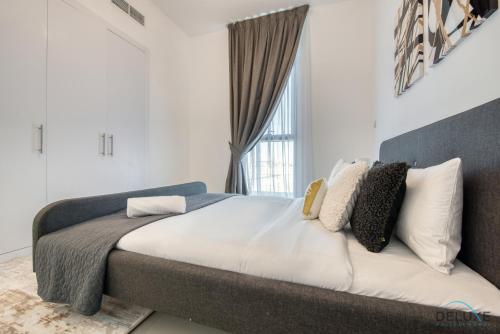 a bedroom with a bed with white walls and a window at Ideal 1BR at The Pulse Residence Icon A1 Dubai South by Deluxe Holiday Homes in Dubai