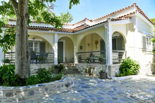 ein Haus mit einem Baum und einer Terrasse in der Unterkunft Vague Summer House in Skiathos-Stadt