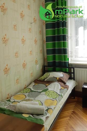 a small bed in a room with a green curtain at mPark Noclegi Śląsk in Chorzów