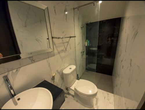 a white bathroom with a toilet and a sink at Puri Mediterania Semarang in Kalibanteng-lor