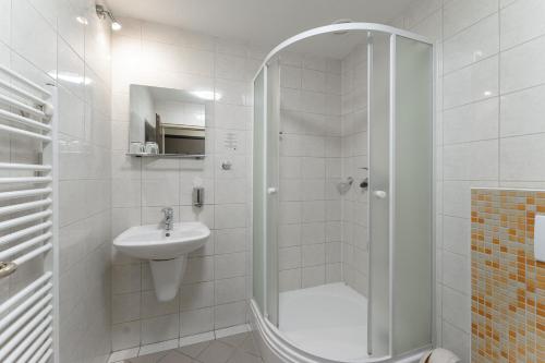 Un baño blanco con ducha y lavabo. en Hotel Amco, en Zábřeh