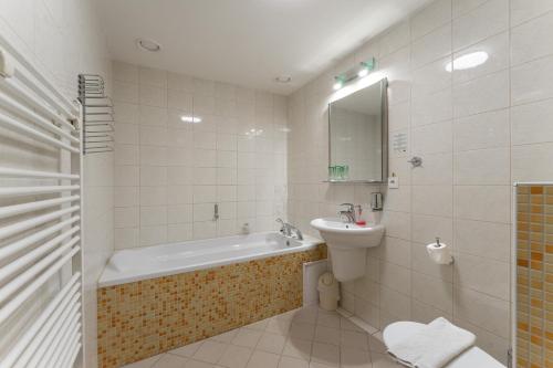 a bathroom with a tub and a sink and a toilet at Hotel Amco in Zábřeh