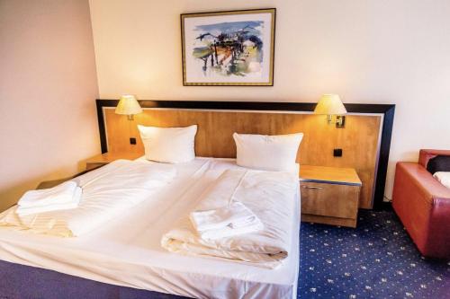 a bedroom with a large white bed and a couch at Apartment Seeblick am Bocksberg - Hahnenklee "Vier Jahreszeiten" in Hahnenklee-Bockswiese