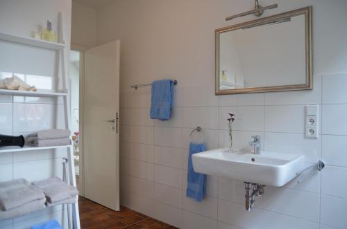 een witte badkamer met een wastafel en een spiegel bij Ferienwohnung im Stadthaus - zwei Schlafzimmer in Winsen