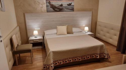 a bedroom with a bed and two tables and a chair at Oasi Perla Del Mare Rooms in Aci Castello