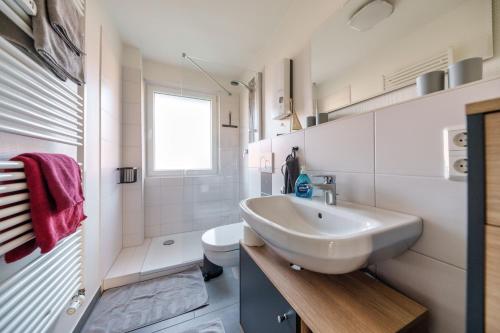 a white bathroom with a sink and a toilet at Fördepause in Flensburg