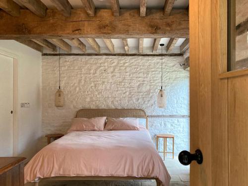 a bedroom with a bed and a brick wall at High Cogges Farm Holiday Cottages - The Granary in Witney