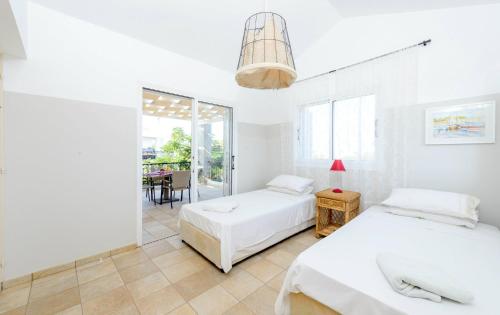 Villa Marilena في بروتاراس: سريرين في غرفة بيضاء مع طاولة