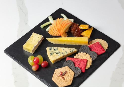 a black plate with different types of cheese and fruit at Loch Rannoch Hotel and Spa in Kinloch Rannoch