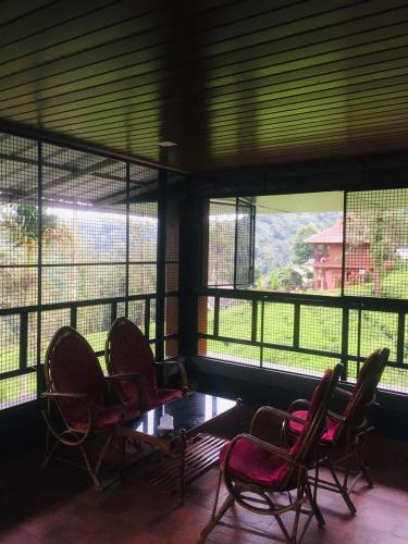 a room with chairs and a table and windows at Vythiri Misty Wind Holiday Homes in Vythiri