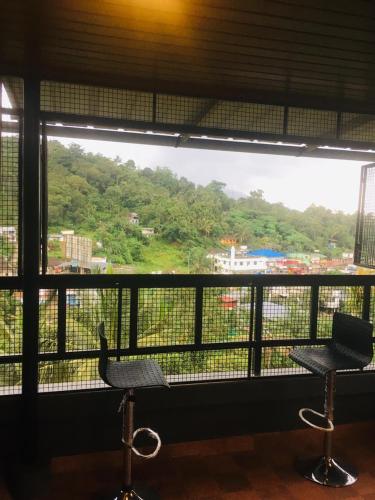 a window with two chairs and a view of a mountain at Vythiri Misty Wind Holiday Homes in Vythiri