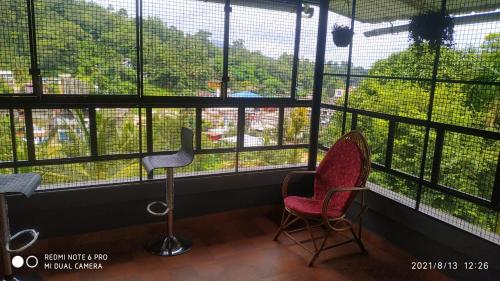 two chairs sitting in front of a large window at LetStay Misty Wind Holiday Homes in Vythiri