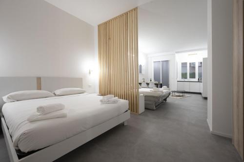 1 dormitorio blanco con 2 camas y sala de estar en GetTheKey Lenzi Suites, en Bolonia