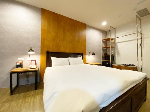 a bedroom with a large white bed and a desk at Taichung Old F Hotel in Taichung