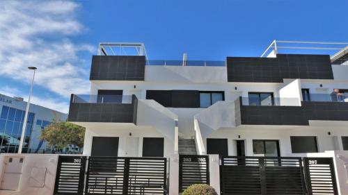 a white building with a black fence in front of it at Luxe appartement met 2 badkamers / zee / zwembad in Lo Pagán
