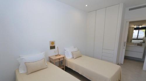 niewielka sypialnia z 2 łóżkami i lustrem w obiekcie Luxe appartement met 2 badkamers / zee / zwembad w mieście Lo Pagán