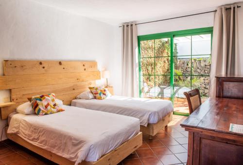 sypialnia z 2 łóżkami i oknem z patio w obiekcie Surfescape Fuerteventura w mieście Lajares