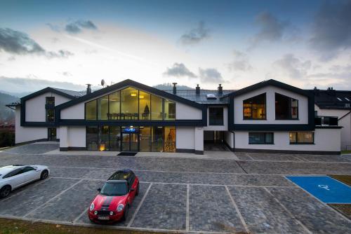 a house with two cars parked in a parking lot at Hotel Jarzębata in Wisła