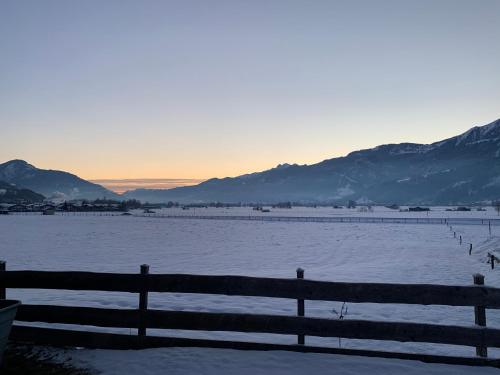 una cerca frente a un campo cubierto de nieve con montañas en Peters Panoramaappartment en Piesendorf