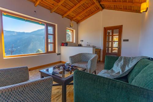 a living room with a table and chairs and a large window at Seclude Ramgarh Willows in Rāmgarh