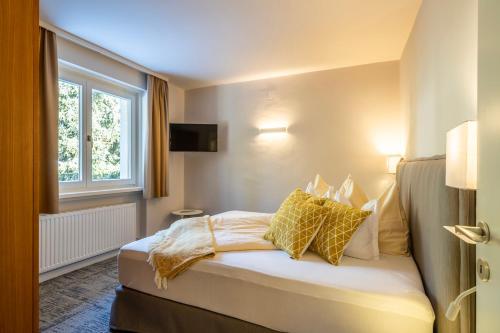 Un dormitorio con una cama con almohadas amarillas y una ventana en Gästehaus Schusser an der Therme, en Bad Kleinkirchheim