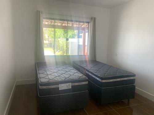 two beds sitting in a room with a window at Faith Home 2 in Arraial do Cabo