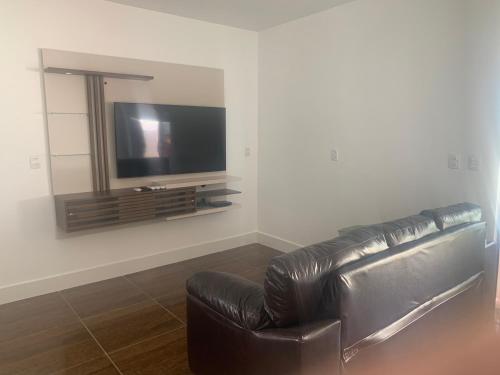 a black leather couch in a living room with a television at Faith Home 2 in Arraial do Cabo