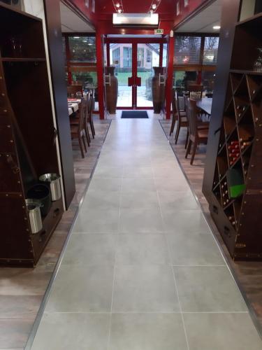 a dining room with a tile floor and tables and chairs at The Originals City, Hôtel Éden, Rouen Nord in Bois-Guillaume