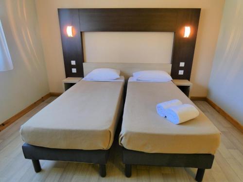 two beds in a room with towels on them at Hôtel Azur Saint Junien Cit'Hotel in Saint-Junien