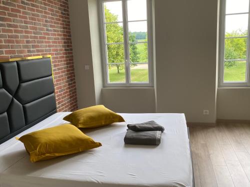 een groot wit bed met gele kussens in een kamer bij Logis Poussard in Arthenac