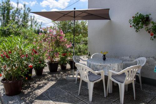a table and chairs with an umbrella and some plants at Apartment Mia in Donja Pačetina