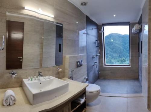 uma casa de banho com um lavatório, um WC e uma janela. em The Jungle Mountain Retreat em Mundaghat 
