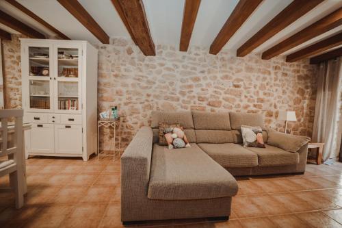 a living room with a couch and a stone wall at Ca La Leonor, Ecoturisme Terra Alta in Bot