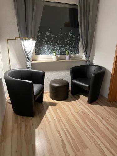 2 Stühle und ein Hocker in einem Zimmer mit Fenster in der Unterkunft Apartment 22 in Kirchhain