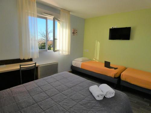 a hotel room with two beds and a television at Hôtel Azur Saint Junien Cit'Hotel in Saint-Junien