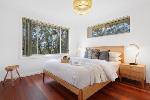 a white bedroom with a bed and two windows at Cliff Haven Retreat in Katoomba