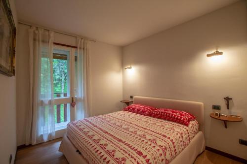 um quarto com uma cama com almofadas vermelhas e uma janela em L'Atelier du Temps - Joya Flat em Courmayeur