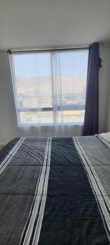 1 dormitorio con 1 cama y ventana grande en Edificio Bulnes - Cavancha, en Iquique