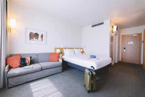 a hotel room with a bed and a couch at Novotel Venezia Mestre Castellana in Mestre