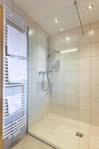 a bathroom with a glass shower with white towels at Gasthaus Posch in Miesbach