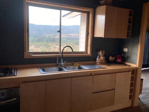a kitchen with a sink and a window at CABAÑA DE CAMPO in Cuncumén