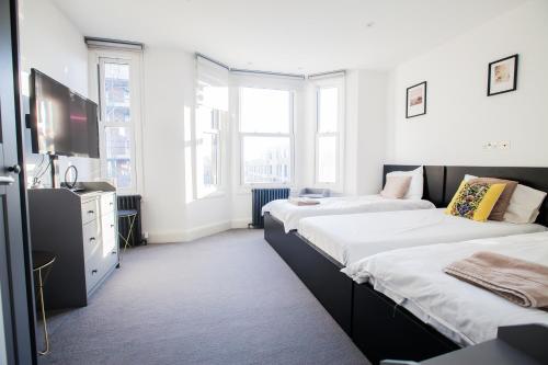 a room with two beds and a tv at Surbiton Luxury Garden House 19A in Surbiton