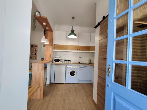 uma cozinha com electrodomésticos brancos e uma porta azul em Largo A2 em Alcácer do Sal