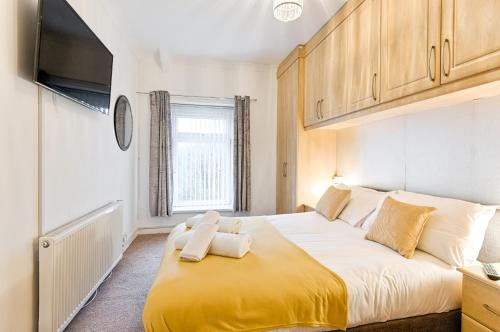 a bedroom with a large bed with a yellow blanket at Spacious home with parking - TV in Every Bedroom! in Swansea