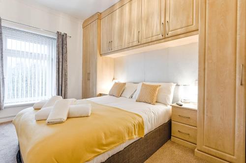 a bedroom with a large bed with a yellow blanket at 5BRM - Off Road Parking - 3 Bath - Garden in Swansea
