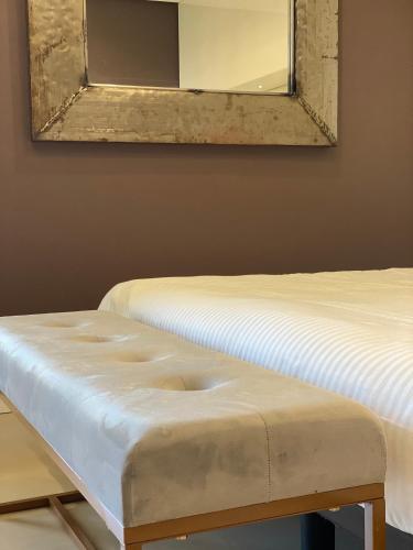 a mirror above two beds with a bench in a room at Gran Paradiso Hotel Spa in San Giovanni Rotondo