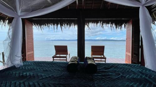 a bed in a room with a view of the ocean at Nyande Raja Ampat in Pulau Mansuar