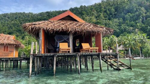 a house on a pier with chairs on the water at Nyande Raja Ampat in Pulau Mansuar